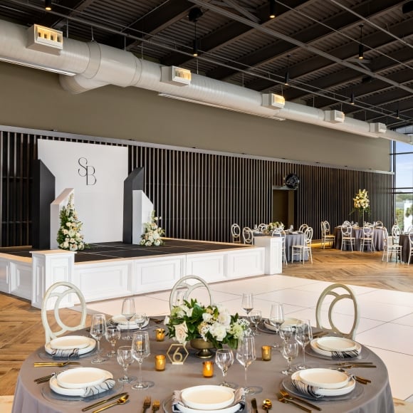 Seaside Vista set up for a wedding reception with round tables and a dance floor with a stage