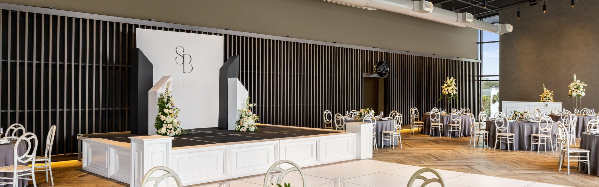 Seaside Vista set up for a wedding reception with round tables and a dance floor with a stage