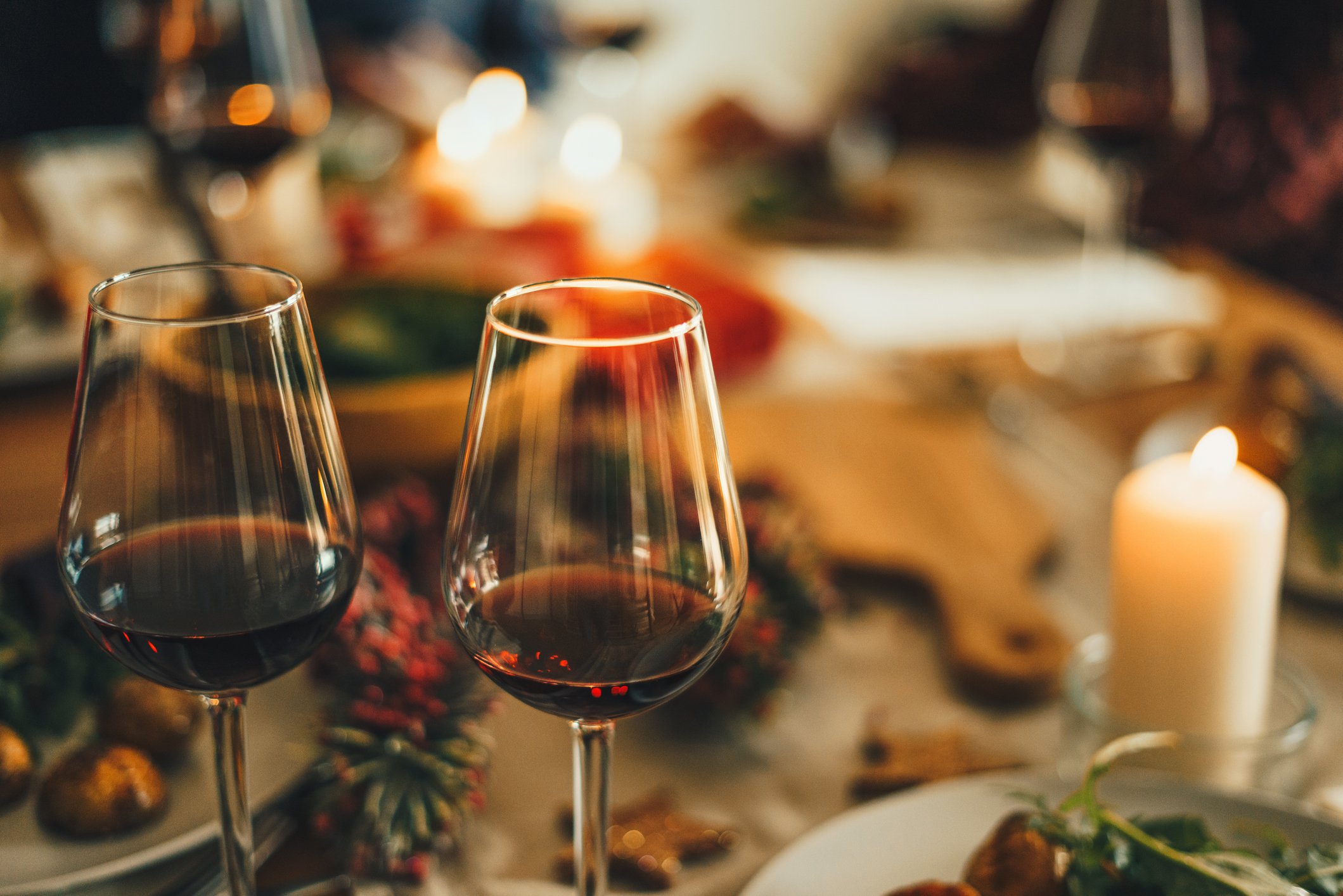 Two glasses of red wine overtop a blurred out Holiday meal spread