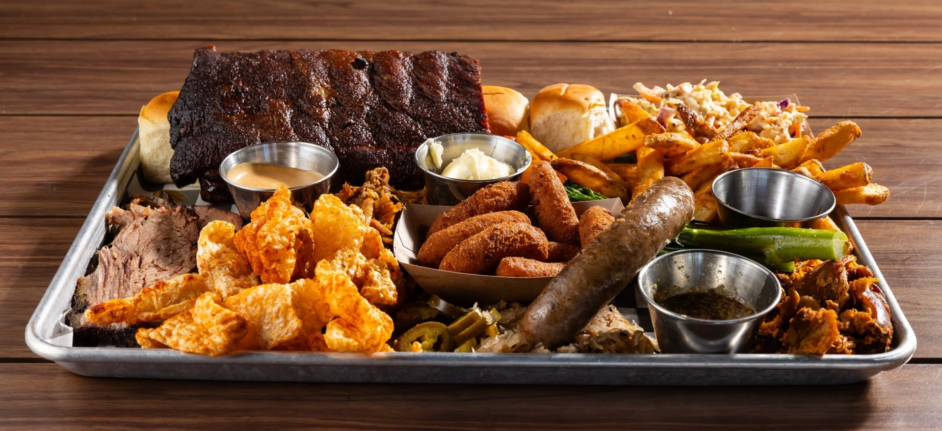 Black Drum Brewing Small BBQ Board consisting of 1/2 rack of ribs, sweet rolls, Cole slaw, French fries, broccolini, pulled chicken, pulled pork, brisket, pork skins, bratwurst, and hush puppies