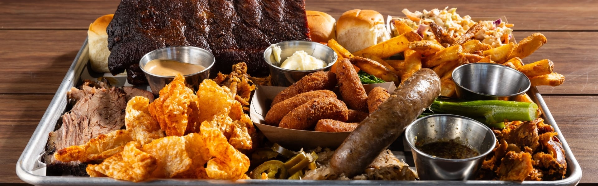 Black Drum Brewing small BBQ Board including a 1/2 rack of ribs, sweet rolls, Cole slaw, French fries, pulled pork, brisket, pulled chicken, bratwurst, pork skins, and hush puppies
